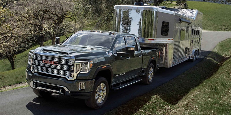 GMC Sierra HD towing large trailer on rural road.