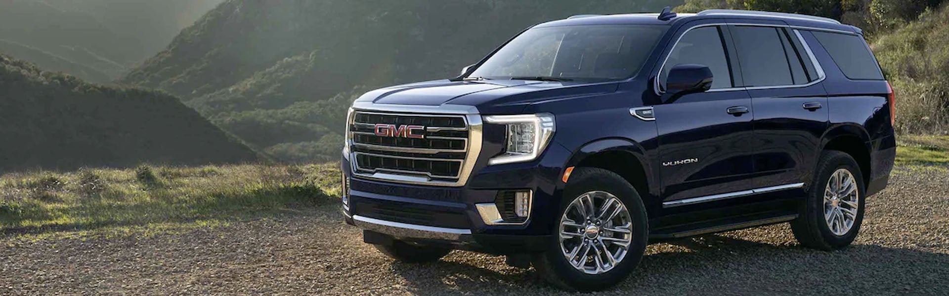 Blue GMC Yukon parked on hills near grass