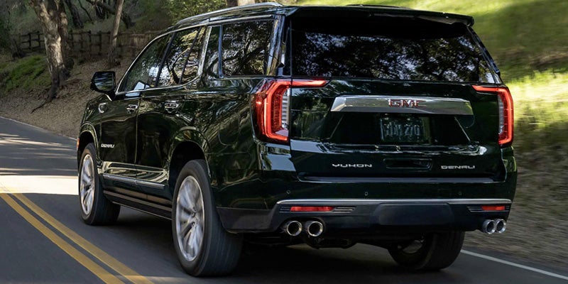 GMC Yukon running on road between jungle and hills