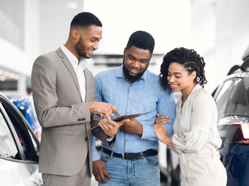 Couple working with a sales representative to look over vehicle options - Pogue GMC in POWDERLY KY